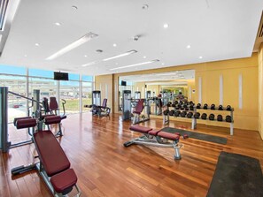 Ein Fitnessraum mit Cardiogeräten, Kurzhanteln und einer Spiegelwand.