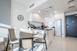 A modern kitchen with a central island, white cabinetry, and a black clock on the wall. - Elegant 2BR in Tower 108 Jumeirah Village Circle by Deluxe Holiday Homes (Dubai)