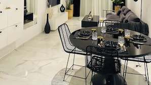 Un salon moderne avec un coin repas, comprenant un téléviseur à écran plat, un canapé, une table à manger avec des chaises et une plante en pot.