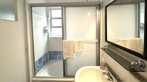 A bathroom with a shower, a sink, and a mirror. - Bright Apartment with Terrace to Faculties (Buenos Aires)