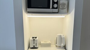 A kitchenette with a microwave, toaster, and coffee maker on a white countertop. - Bright Apartment with Terrace to Faculties (Buenos Aires)
