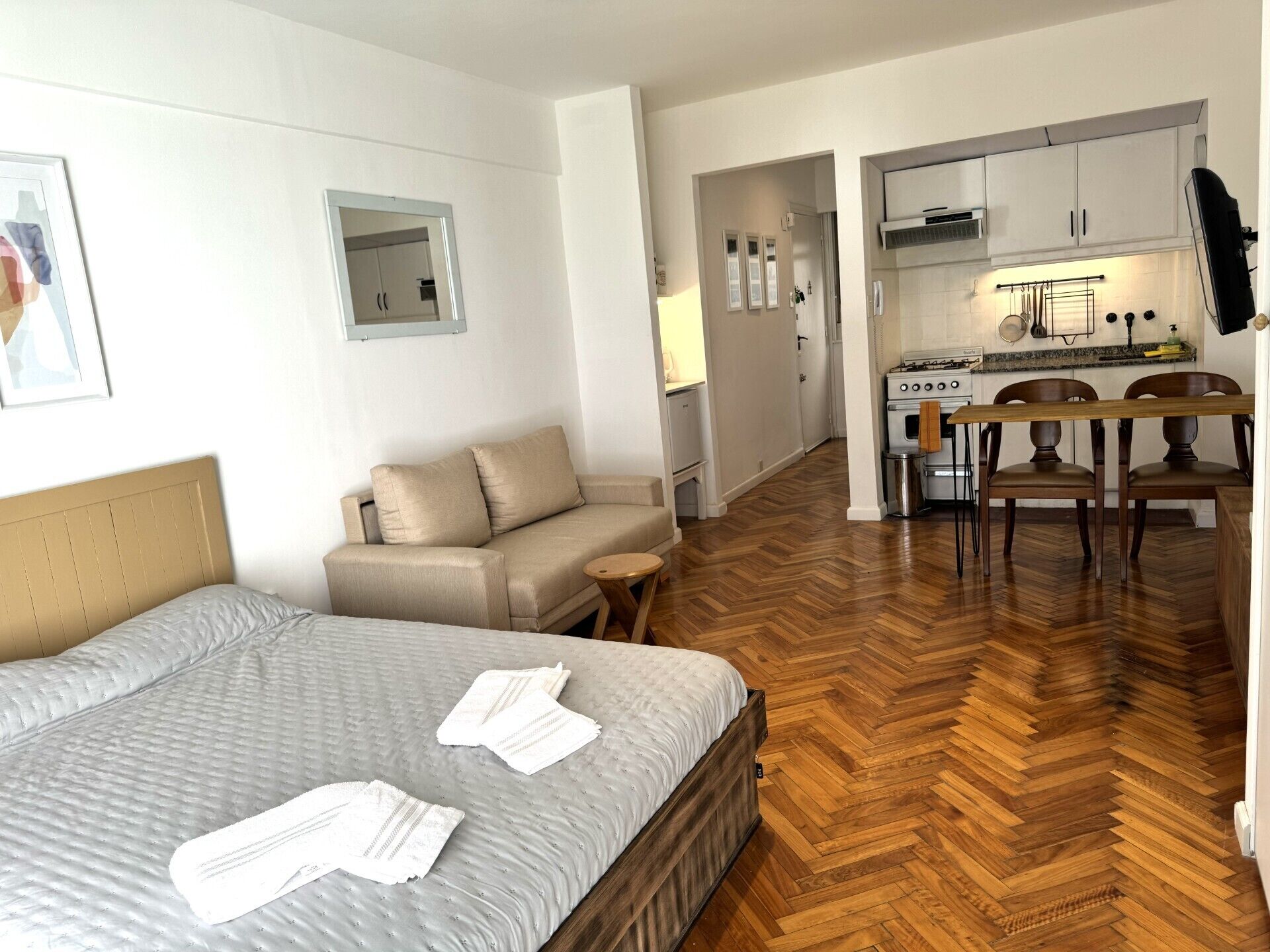 Een hotelkamer met een bed, een slaapbank, een tafeltje en een kitchenette.