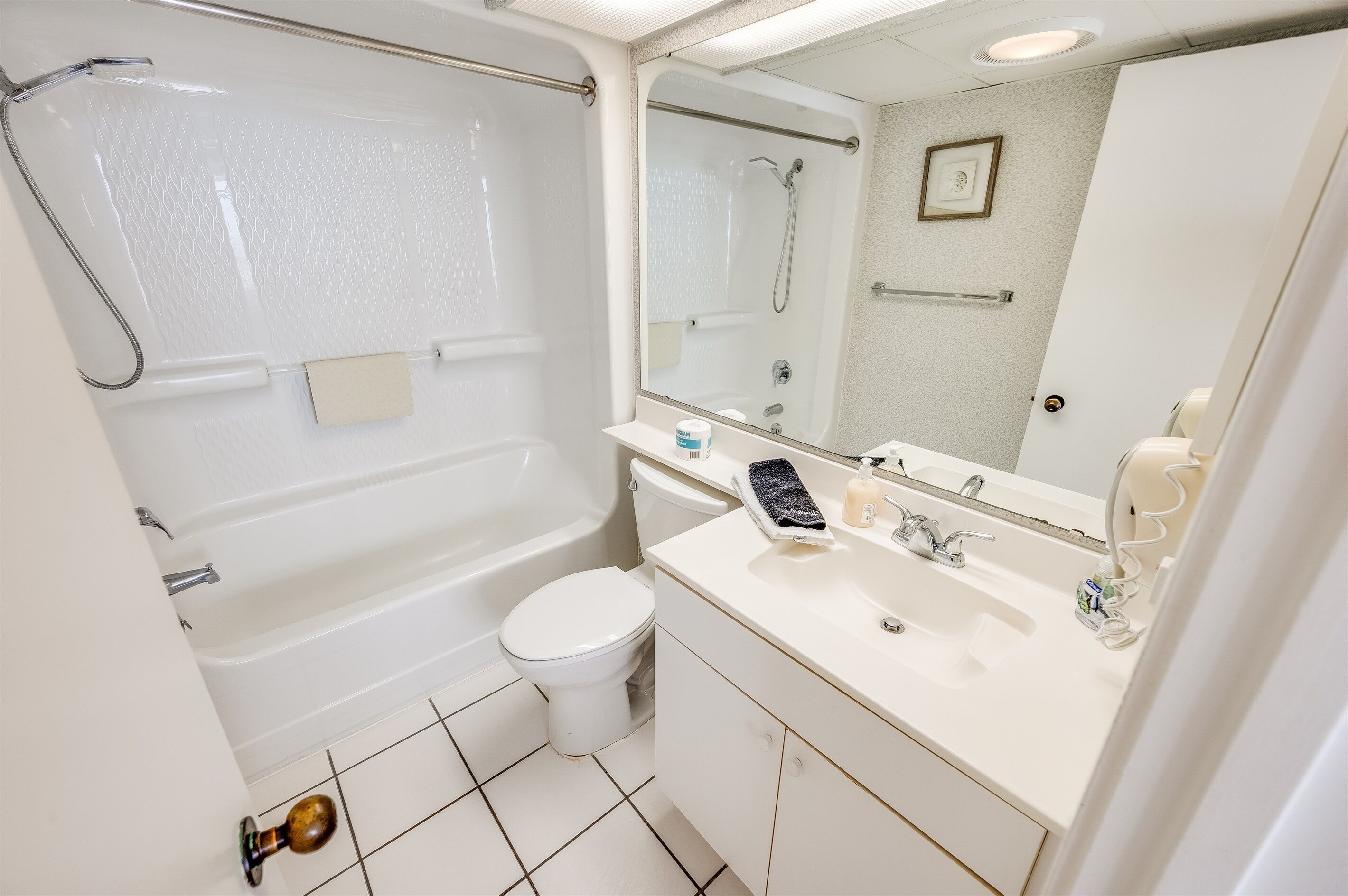 A bathroom with a bathtub, toilet, sink, and mirror.