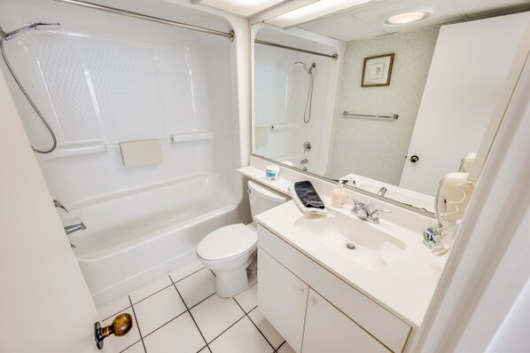 A bathroom with a bathtub, toilet, sink, and mirror.