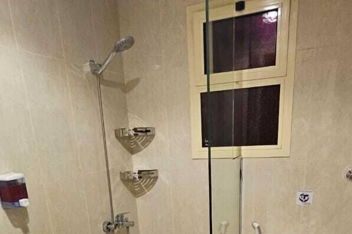 A bathroom with a glass-enclosed shower, a toilet, and a sink.