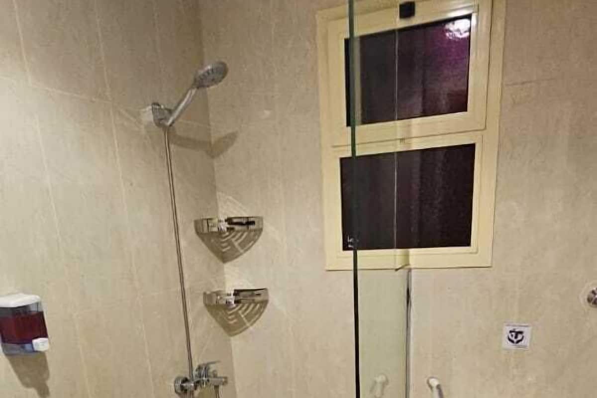 Standaard driepersoonskamer | Badkamer | Een douche, handdoeken, zeep, shampoo