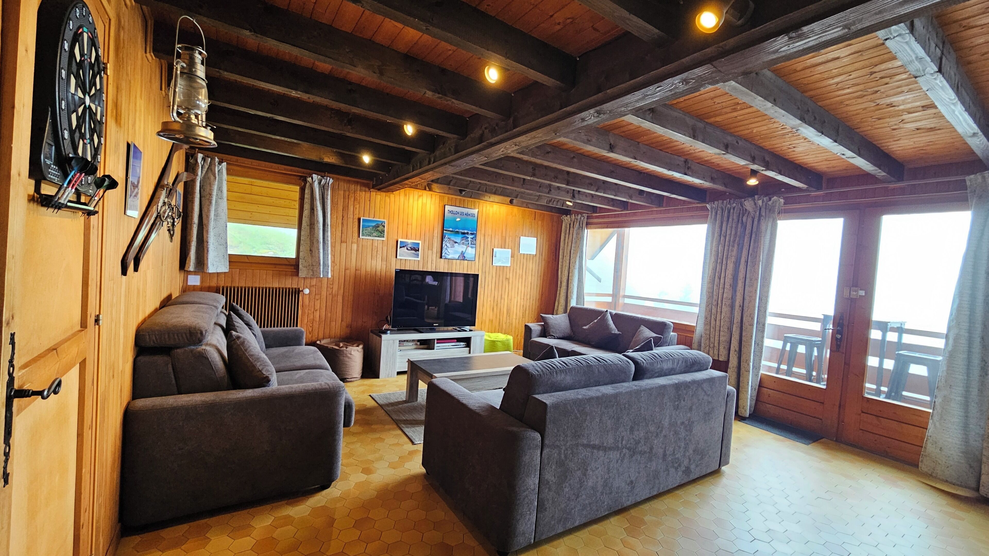 L’intérieur d’un chalet accueillant, avec des murs en bois, un téléviseur et des sièges confortables.