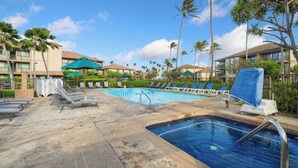 A pool area with lounge chairs, umbrellas, and a small hot tub. - Pono Kai F207 Oceanview AC, POOL, JACUZZI, BBQ, TENNIS (Kapaa)