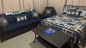 A bedroom with a bed, a sofa, a chair, and a small table.