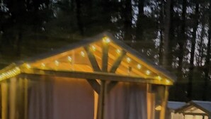 A small wooden cabin with a sloped roof and a porch, surrounded by trees.