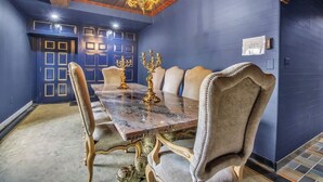 Une salle à manger avec une table en marbre, des chaises décorées et un lustre.