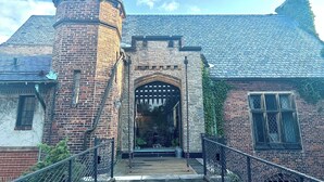 Un bâtiment historique doté d’un portail en arc de pierre, d’une tour en briques et d’un toit à forte pente.