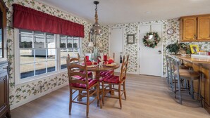 A dining area with a round table, red upholstered chairs, and a chandelier.