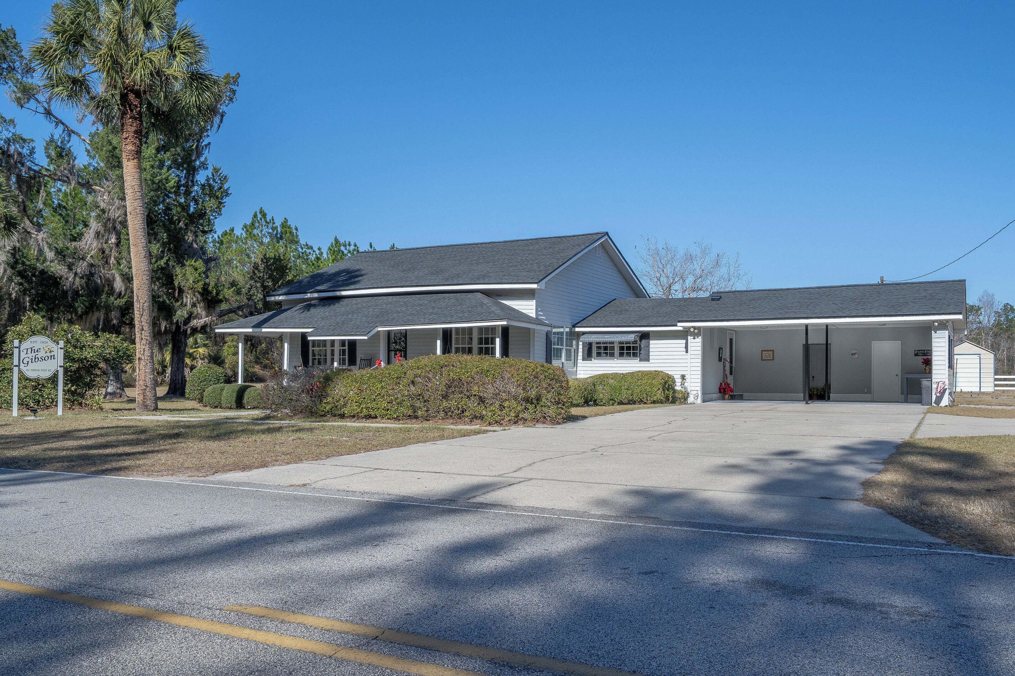 A two-story house with a garage, a covered driveway, and a well-maintained lawn.
