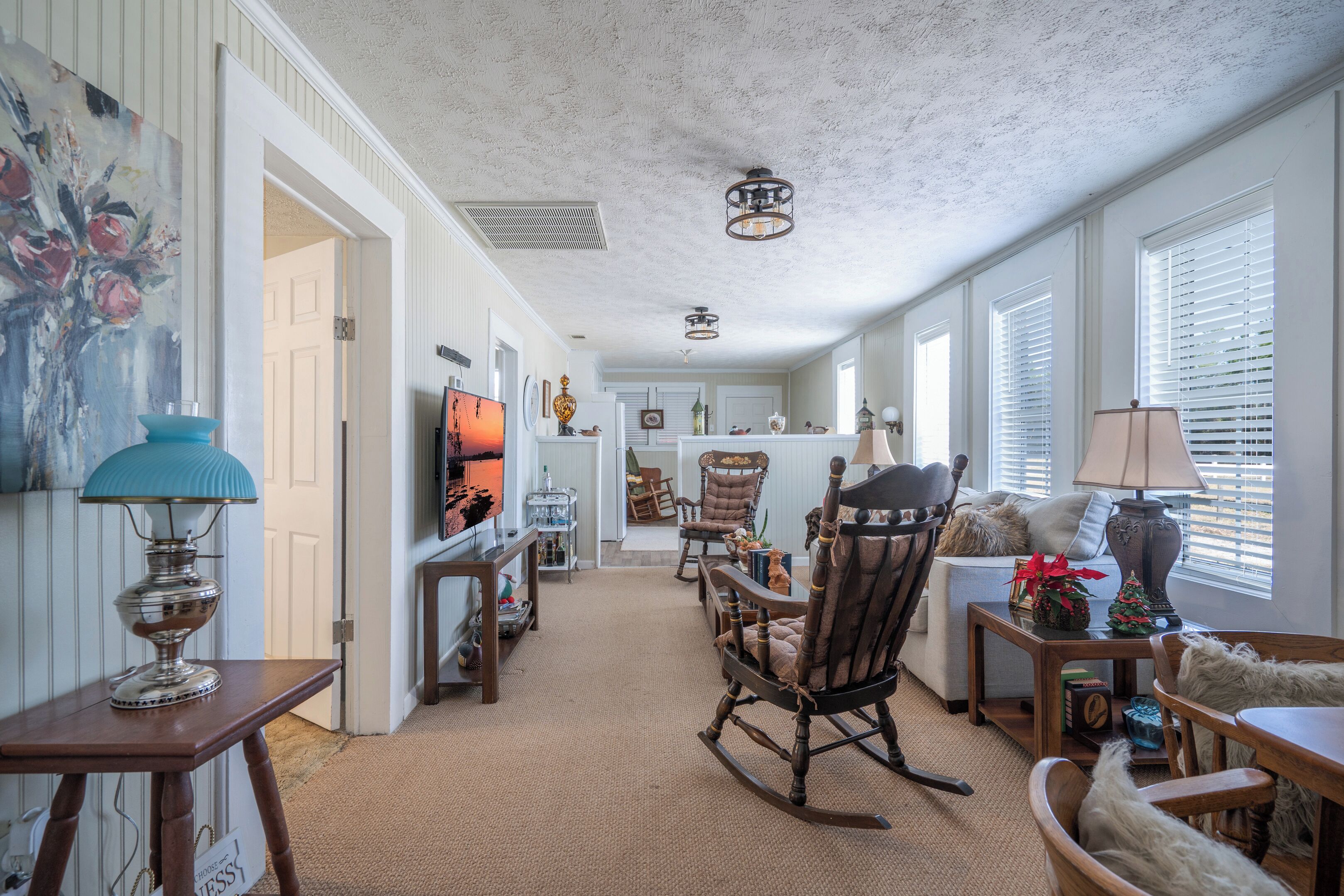 A spacious living room with a fireplace, a dining area, and a kitchen in the background.