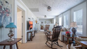A spacious living room with a fireplace, a dining area, and a kitchen in the background.