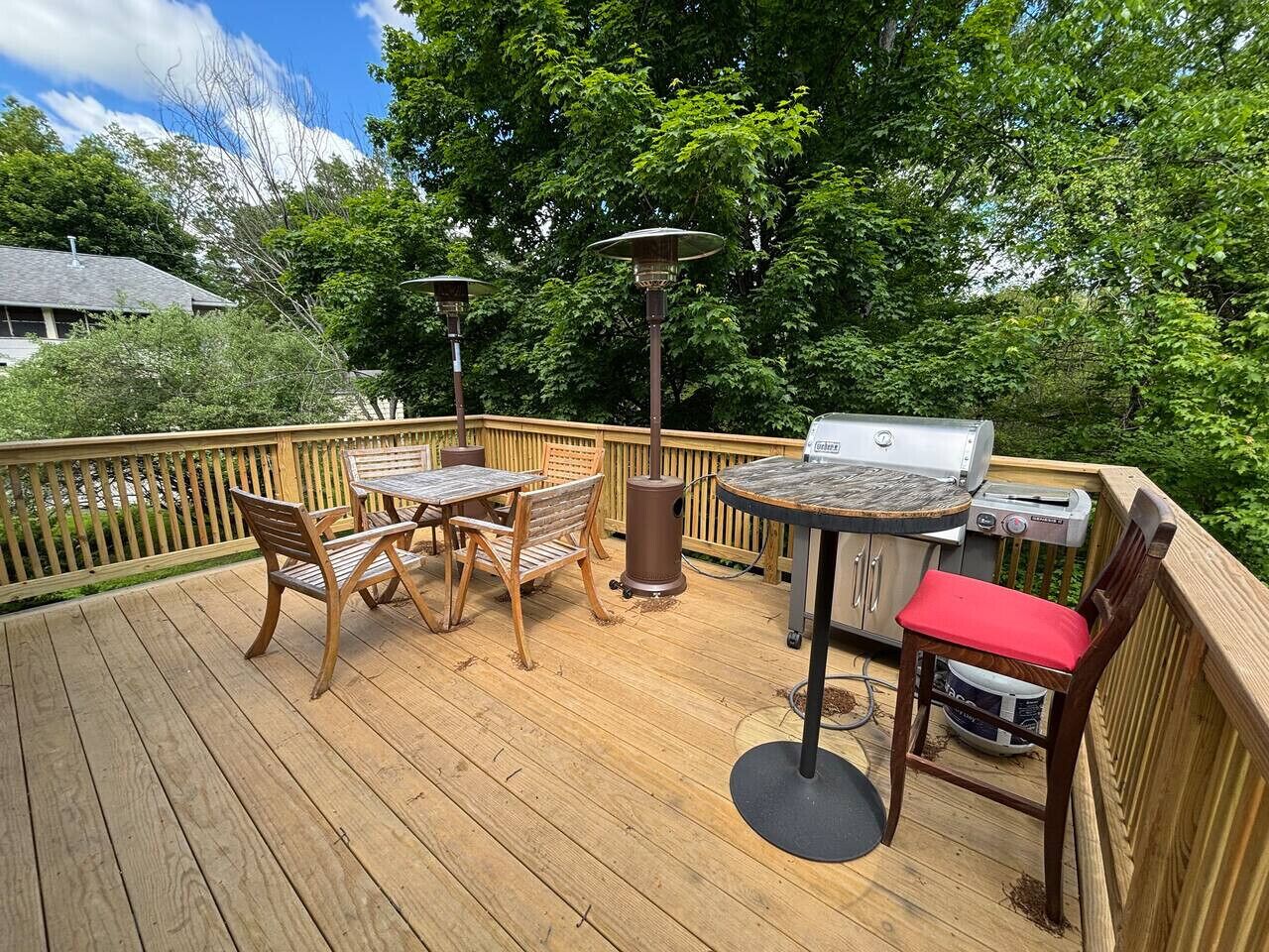 A wooden deck with a grill, a table, and chairs.