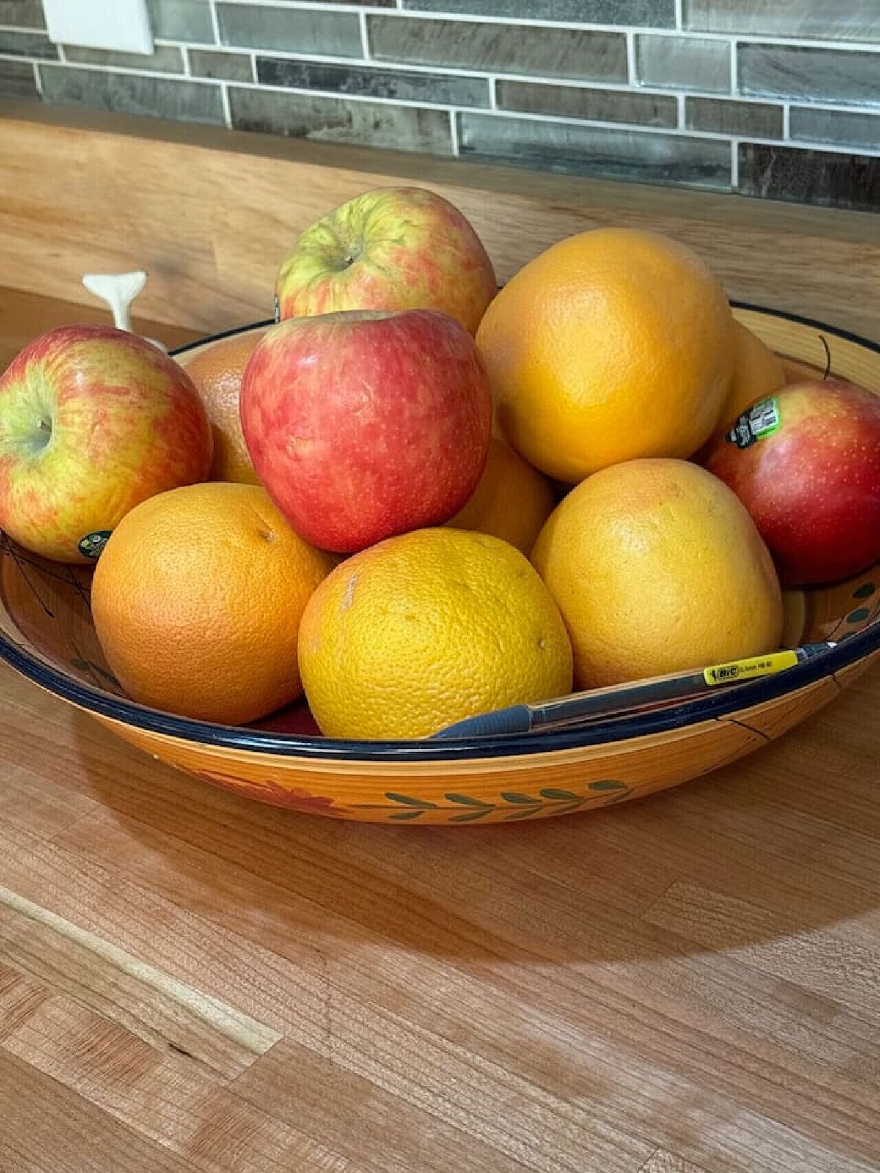 Un cuenco con manzanas y naranjas sobre una mesa de madera.