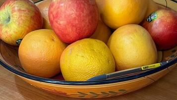 Un cuenco con manzanas y naranjas sobre una mesa de madera.