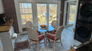 A kitchen with a dining table, chairs, a ceiling fan, and a large window. - The Sun Filled Cozy Creamery (Plainville)