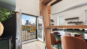 Een moderne keuken met stadszicht, een eethoek met stoelen, en een plant.