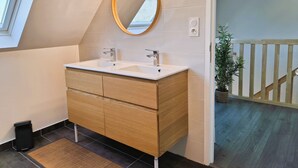 A modern bathroom with a wooden vanity, two sinks, and a large mirror. - Chic and warm!  Modern house near the beach Baie de Morgat (Crozon)