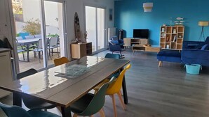 A spacious living area with a dining table, colorful chairs, a blue sofa, and a bookshelf. - Chic and warm!  Modern house near the beach Baie de Morgat (Crozon)