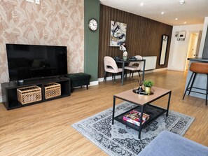 Un salon moderne doté d’un téléviseur à écran plat, d’une table basse et d’un coin repas avec des chaises et une table.