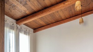 Ein Schlafzimmer mit Holzboden, einem Bett mit weißem Kopfteil und einer Pendelleuchte.
