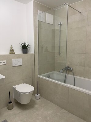 A modern bathroom with a glass-enclosed shower, a bathtub, a toilet, and a sink. - Luxury City Apartment in Munich (München)