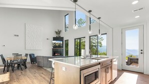Una cocina moderna con una isla grande, electrodomésticos integrados y amplios ventanales que ofrecen vistas al exterior.