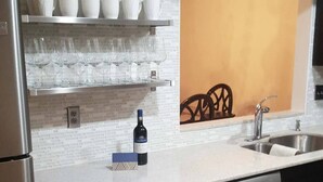 Une cuisine moderne dotée d’un réfrigérateur à vin encastré, d’appareils électroménagers en acier inoxydable et d’un pare-feu avec un motif en briques.