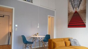 Un salon moderne avec un canapé jaune, deux fauteuils bleus et une petite table ronde.