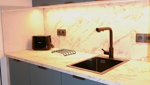 Une cuisine dotée d’un plan de travail en marbre, d’un évier noir et d’une machine à café.