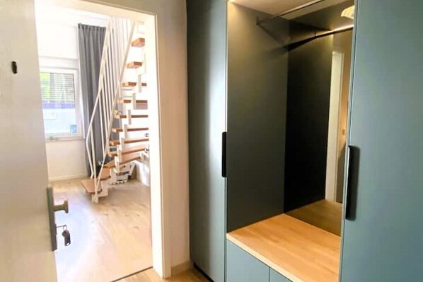 A modern interior with a wooden staircase, a grey wardrobe, and a wooden floor.