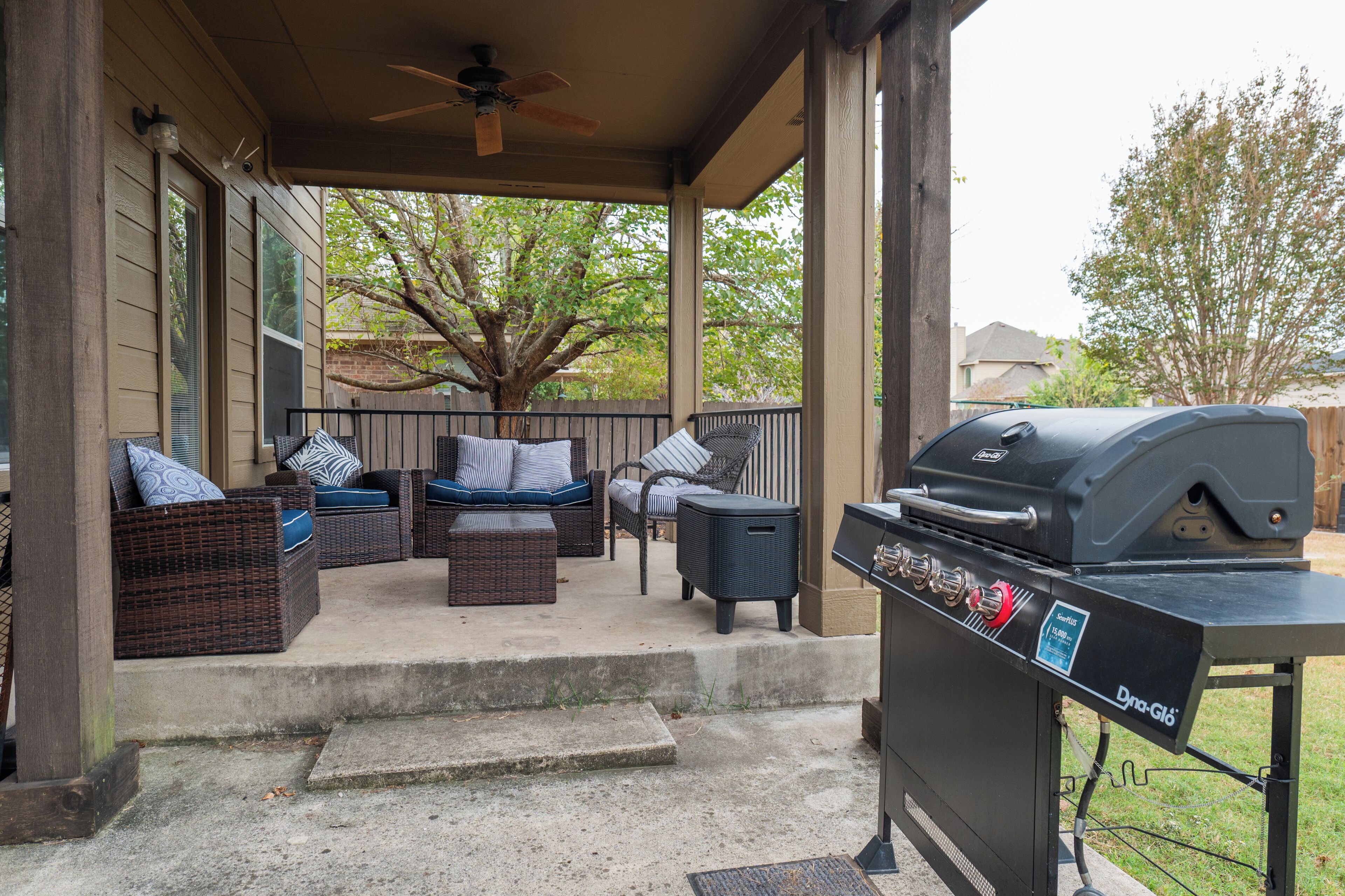 An outdoor patio with wicker furniture, a grill, and a ceiling fan.