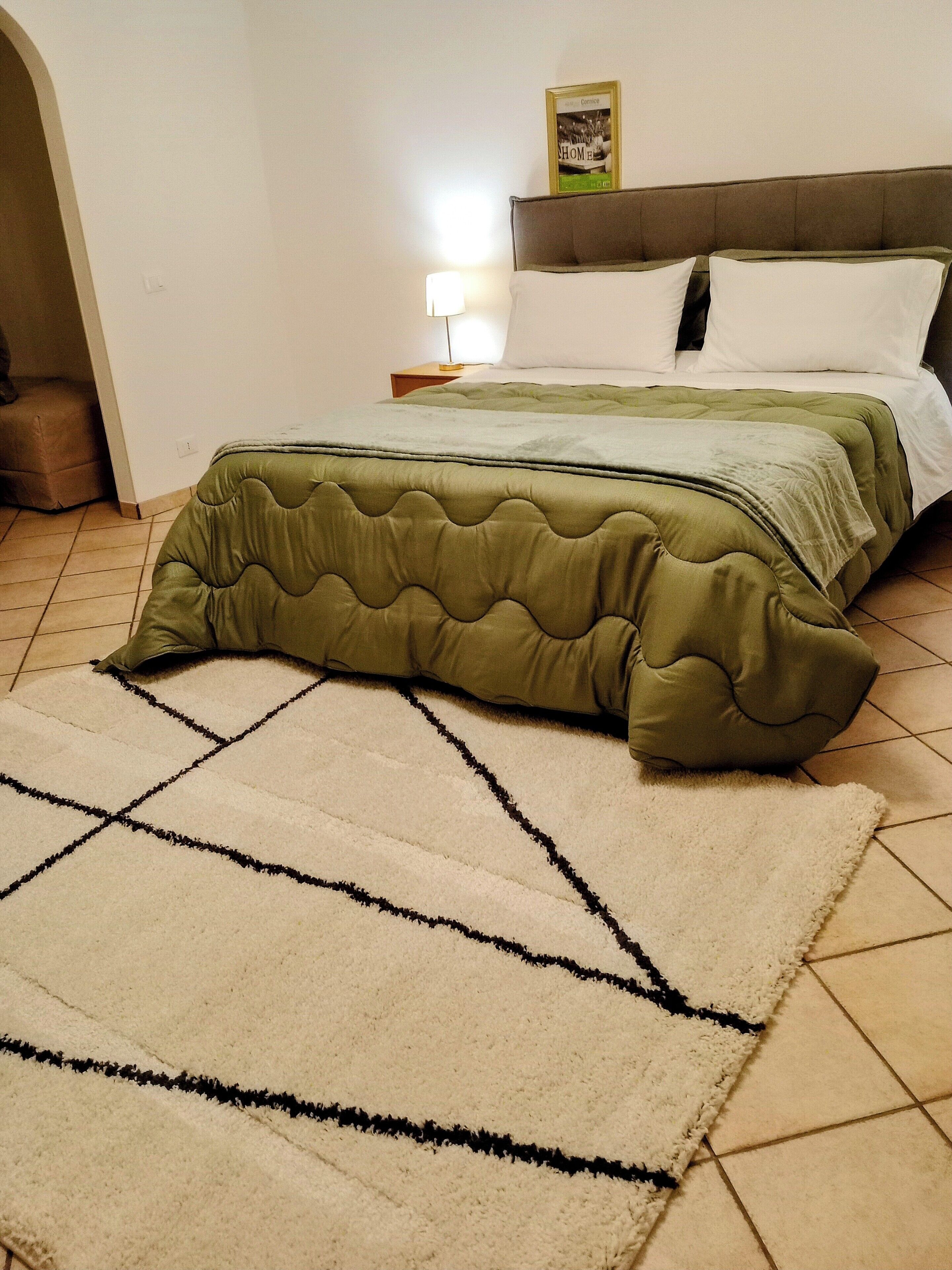 Una camera da letto con un letto, un comodino, una lampada e un quadro appeso al muro.