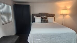 A bedroom with a bed, a bedside lamp, a dark wardrobe, and a window with blinds. - Charming barn with WiFi and AC in enchanting Intercession City (Intercession City)