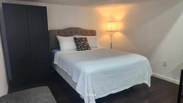 A bedroom with a bed, a nightstand, a lamp, and a wardrobe. - Charming barn with WiFi and AC in enchanting Intercession City (Intercession City)