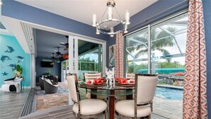A dining area with a glass table, four chairs, and a chandelier. - Boaters Dream, open water, heated pool, sleeps 6 (Gulf cove)