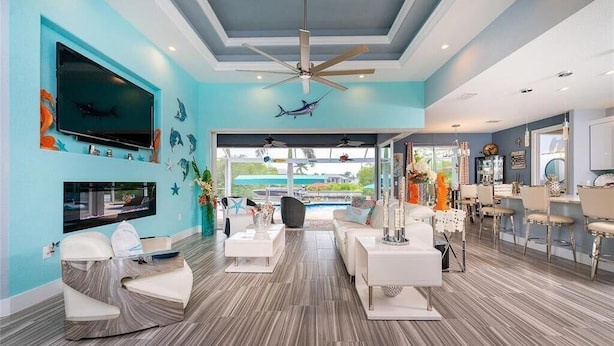 A spacious living area with a large TV, ceiling fan, and a view of the pool. - Boaters Dream, open water, heated pool, sleeps 6 (Gulf cove)