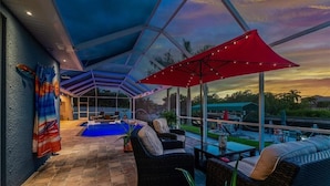 A covered outdoor area with a pool, wicker furniture, and umbrellas. - Boaters Dream, open water, heated pool, sleeps 6 (Gulf cove)