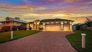 A two-story house with a garage, a driveway, and a well-maintained lawn. - Boaters Dream, open water, heated pool, sleeps 6 (Gulf cove)
