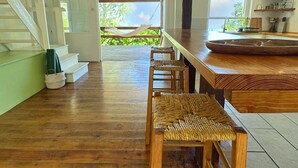 Eine geräumige Küche mit Holzarbeitsplatte, einem großen Esstisch aus Holz und Blick ins Freie durch eine Glastür.