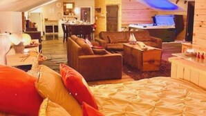 Um quarto estilo sótão com uma cama grande, um sofá e uma área de jantar.