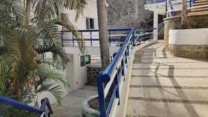 A staircase with blue railings leading to a building with a stone wall and a palm tree.