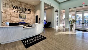 Un mostrador de recepción en Windsor Island Resort, con un fondo de pared de piedra, una pantalla digital y un felpudo.