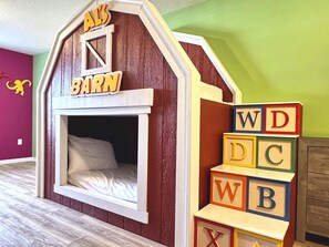 A children's play area with a barn-themed bed and alphabet blocks.