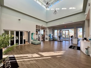 A spacious lobby with a high ceiling, large windows, and a reception desk.