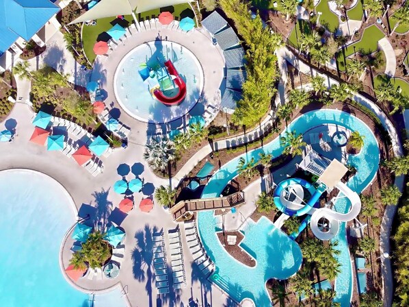 An aerial view of a resort with a large pool, water slides, and sun loungers.